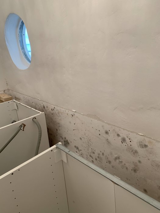 Vägg delvis målad med våtrumsfärg ovanför vit IKEA underskåp och ommålad, fläckig del under.