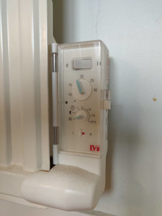 Termostat på element med symboler för olika inställningar, inklusive temperaturskala och lägesväljare.