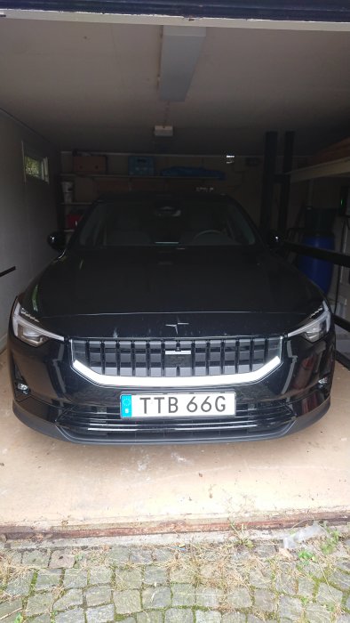 Ny svart bil parkerad i ett garage, registreringsskylt TTB 66G synlig.
