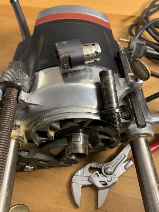 Närbild på en robust elektrisk överfräs med en markerad 12 mm spännhylsa, lös bredvid maskinen, och en inställbar skiftnyckel.