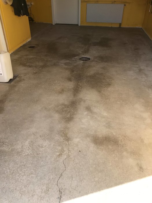 Renoverat gammalt betonggolv som torkat, med synliga lagningar och täckpapp längs kanterna.