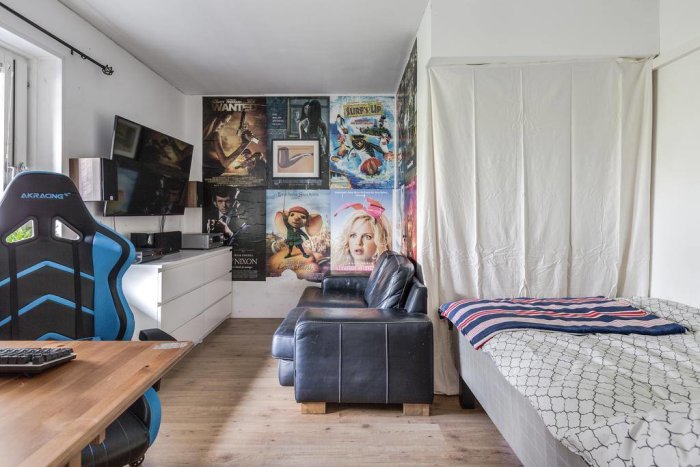 Inredd vind i radhuset före renovering med säng, filmplanscher, skrivbord och gamingstol.