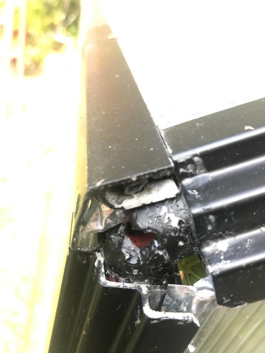 Närbild på en skadad svart plastdel med skruvfäste och ihåligt inre.