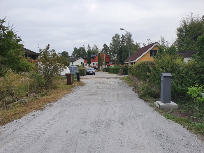 En grusväg som leder till ett hus, med en nyasfalterad väg som slutar högre än garageuppfarten.