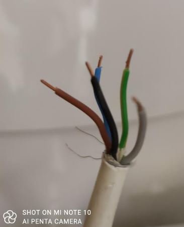 Avskalad elektrisk kabel med exponerade brun, blå, grön, och svart tråd.