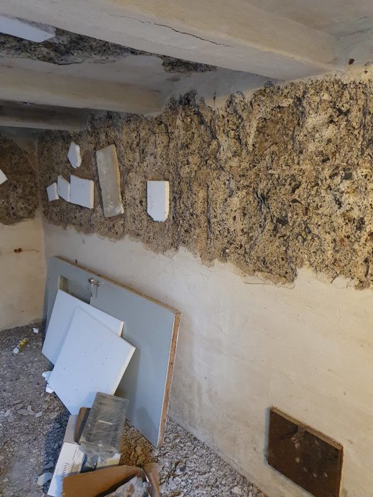 Renoveringsprojekt där frigolit limmats i djupa hål i en vägg, med byggmaterial på golvet.