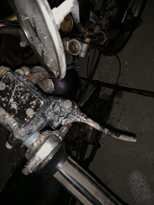 Närbild på en moped skivbroms och handbroms med synliga slitage och korrosion.