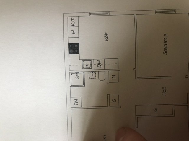 Planritning av en lägenhet med markerade köksinredningar som kyl/frys, skåp och vask.