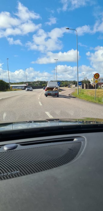 Släpvagn med obunden kåpa lastad med träplank på en solig väg.