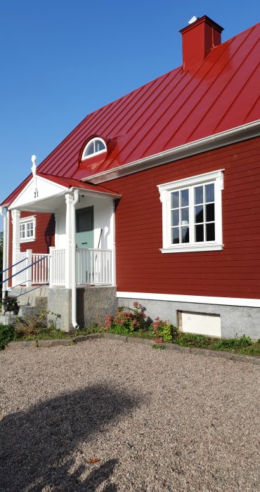 Klassiskt rött hus med vita knutar och en ytterdörr målad i en inte fullt tillfredsställande grönblå nyans.