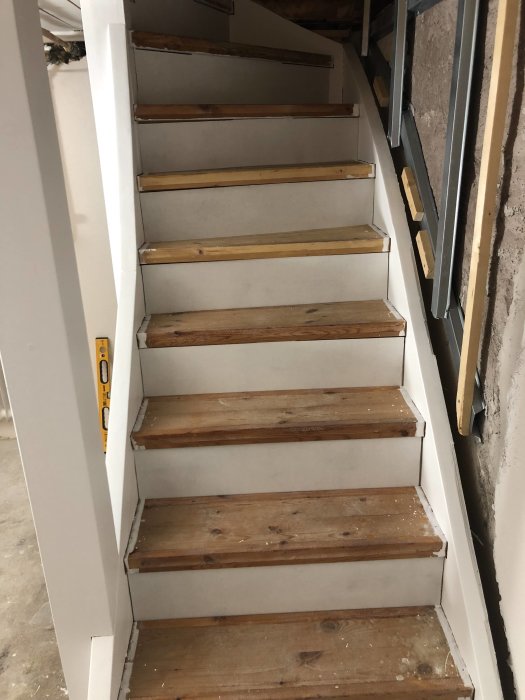 Renoverad källartrappa med stängda sättsteg i ett under konstruktion hem.