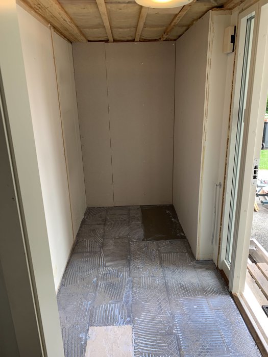 Ett rum under renovering visar slipade golv förberedda med tunnt lager av flytspackel innan klinkerläggning.