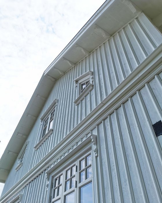 Gavel på nyrenoverat hus med vitmålade plankor och fönster mot en klar himmel.