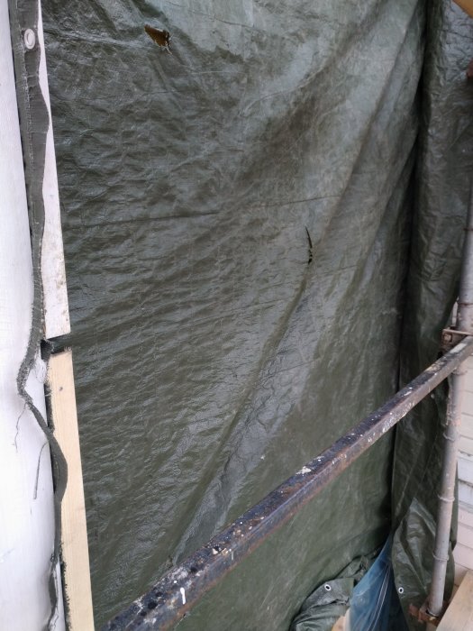 Skyddstäckt väggisolering med synliga hål troligtvis orsakade av fåglar.