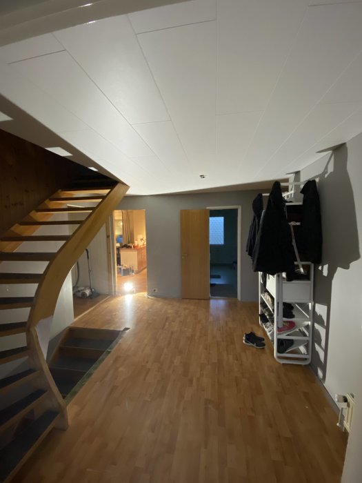 Nyligen färdigställt vitt innertak i ett rum med trätrappa och parkettgolv.