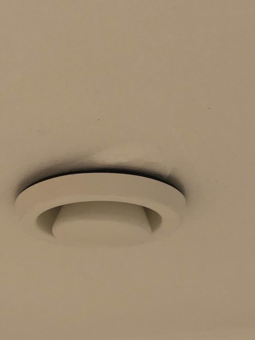 Ventilationsöppning i tak med mjuk bubbla i målarfärgen runt den, misstänkt fuktskada.