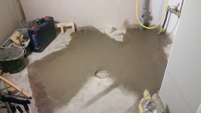 Nyutgjuten betong på källargolv med verktyg och byggmaterial runtomkring.