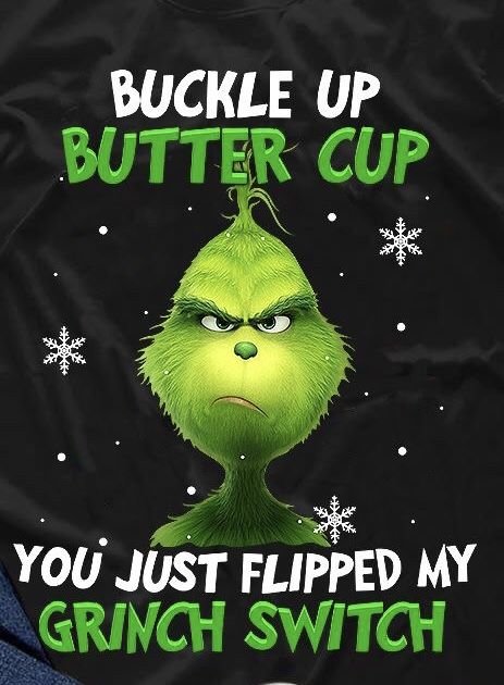 Svart t-shirt med illustration av Grinchen och texten "BUCKLE UP BUTTER CUP YOU JUST FLIPPED MY GRINCH SWITCH" omgiven av snöflingor.