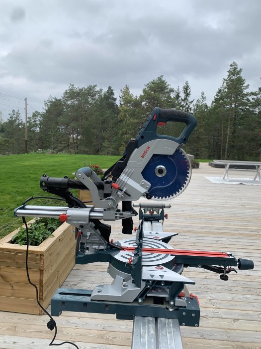 Ny Bosch kap/gersåg monterad på arbetsbänk utomhus med skog i bakgrunden.