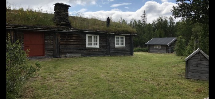 En traditionell fäbodgård med timmerbyggnader, grästak, och omgivande gröna landskap i Imsdalen, Norge.