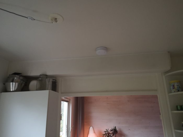 Bild på en köksvägg som möter vardagsrum med synligt ventilationsrör och takdetails.