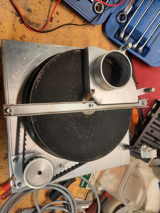 Öppet lock på ventilationsutrustning med synlig rotor och anslutna kablar på verkstadsbänk.