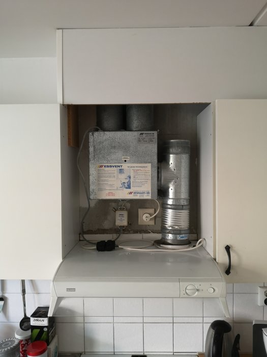 Kökets ventilationshörn med fläkt och tre anslutna rör synliga ovanför spisfläkten.
