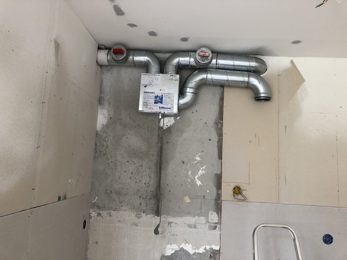 Ombyggd rördragning i kökets hörn med fläktdon och förberedda ytor för skåp och kakel.