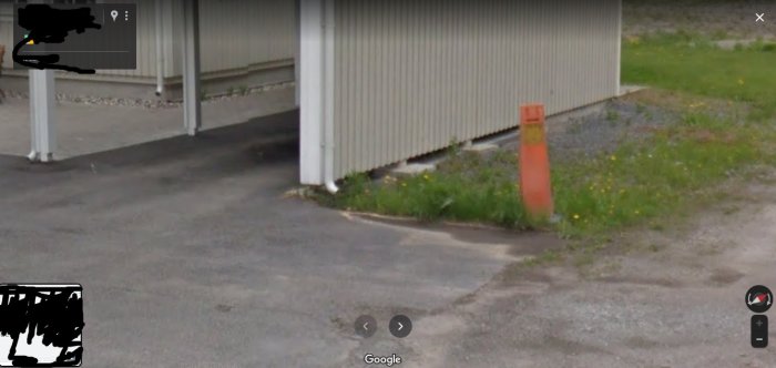Garageinfart där takavvattning från hus och carport syns rinna ut på asfalten.
