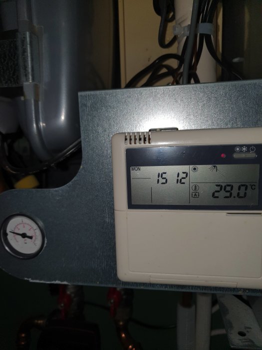 Digital värmeregulator visar 29.0°C, intill en tryckmätare, med oidentifierbara rör och sladdar i bakgrunden.