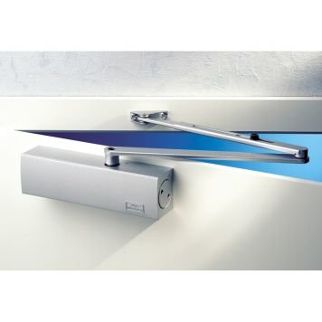 Automatisk dörrstängare monterad på överkant av dörr med justerskruvar synliga.