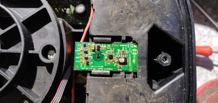 Kompasschippet i en robotgräsklippare syns där det ligger i maskinens främre del, något smutsigt med synlig märkning 'BOSCH AL COMPASS'.