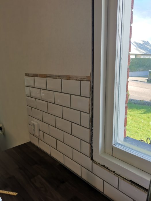 Vitkaklad vägg som möter ett fönster med en 5 mm kant och 10 mm utstickande kakel.