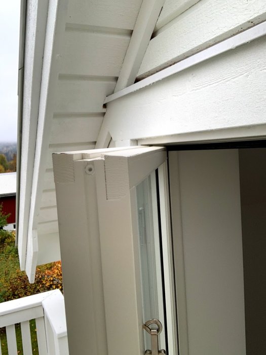 Överst på ett öppet vitmålat fönster som visar karmens ovansida och angränsande takstruktur inomhus.