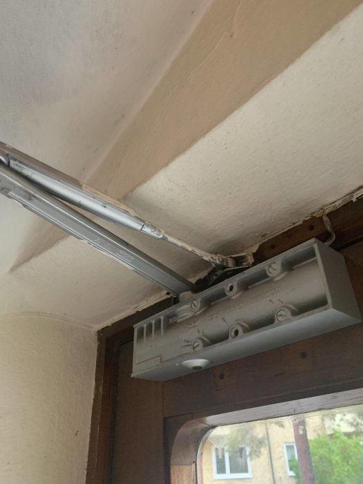 Installation av en elektrisk garageportsöppnare monterad i taket med synlig ledning och mekanism.