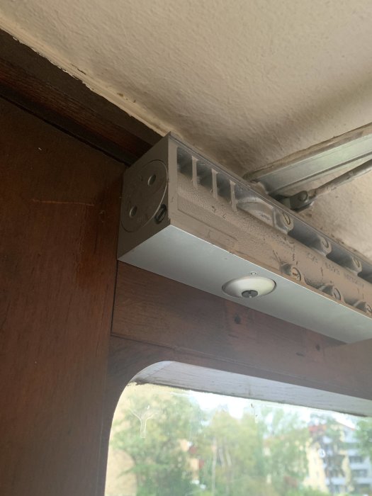 Monterad metallkanal för eldragning längs med en träkarm, nära taket vid ett fönster.