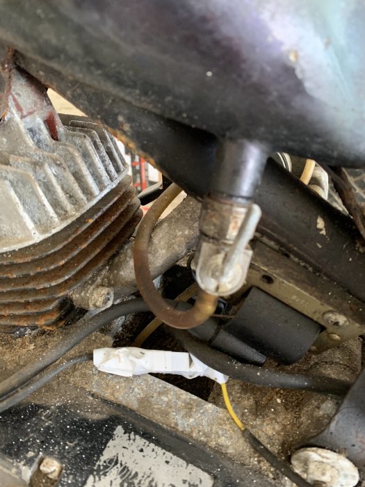 Närbild av smutsig motor med slangen ansluten och tecken på gammal smörja.