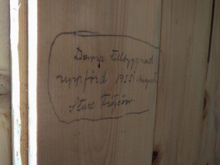 Träplank med handskriven text: "Denna tillbyggnad uppförd 1955 augusti Sture Pettersson.
