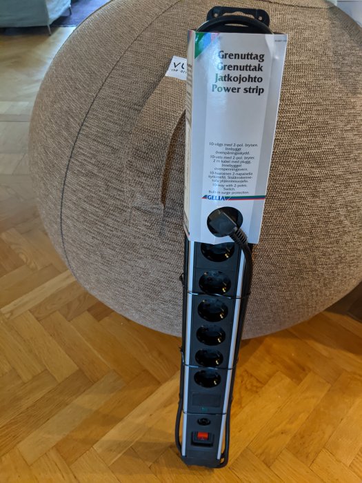 Ny grenuttag med flera uttag står på trägolv, förpackning synlig med texten "Grenuttag Jatkojohto Power strip".