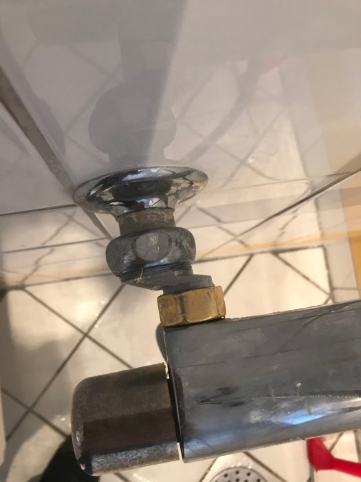 Gammal duschblandare med synliga anslutningsmuttrar och rör vid kakelvägg, i behov av excenterkoppling för ersättning.