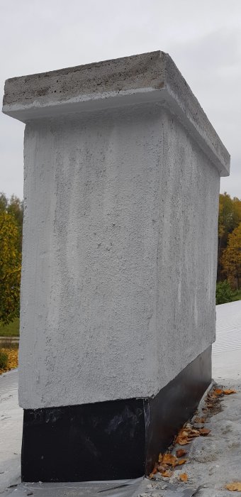 Nykonstruerad skorstenskrona i betong med nedsvarvade ytterkanter och svartfärgad vattentätning nedtill.