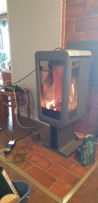 En kamin med öppna lågor inne i ett rum, utrustning för temperaturmätning bredvid.