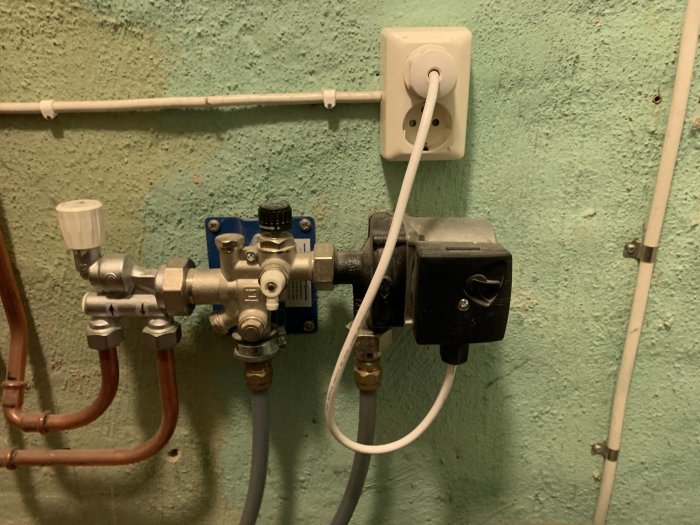 Väggmonterad LK Minishunt M60 för vattenburen golvvärme med anslutna rör och reglerventil.