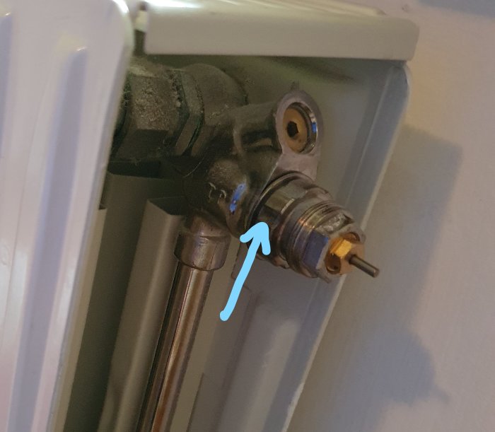 Radiatorventil med en pil som pekar på en specifik del, möjlig plats för åtgärd.