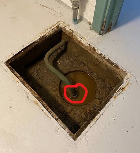 Vattenfylld grop med en inringad mutterliknande föremål i mitten, ansluten till ett rör.