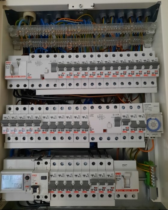 Elcentral med flera säkringsautomater, en energimätare och ett tidur.