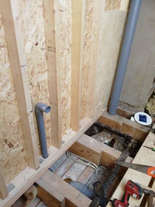 Renovering med reglar, OSB-skivor, isolering och synlig VVS i öppet golv.