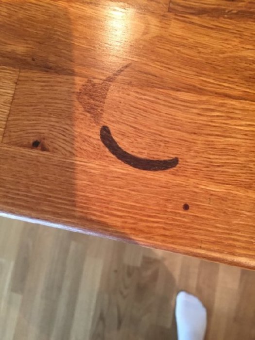 Bänkskiva i trä med mörk fläck efter skada från rengöringsmedel och slät blank yta.