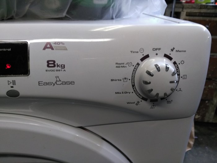 Vit torktumlare med reglage och inställningar, modell EasyCase 8kg EVOG 981 A, mot en suddig bakgrund.