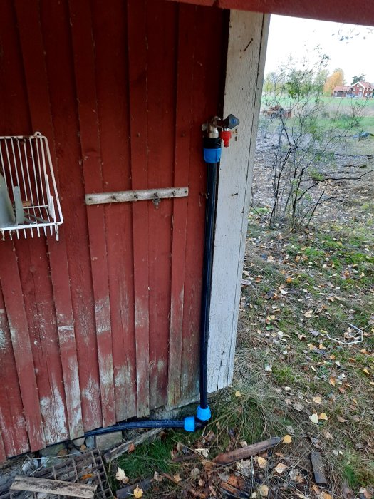 Vattenledning installerad vid röd stuga med PRK i mark och plastkopplingar ovan mark.